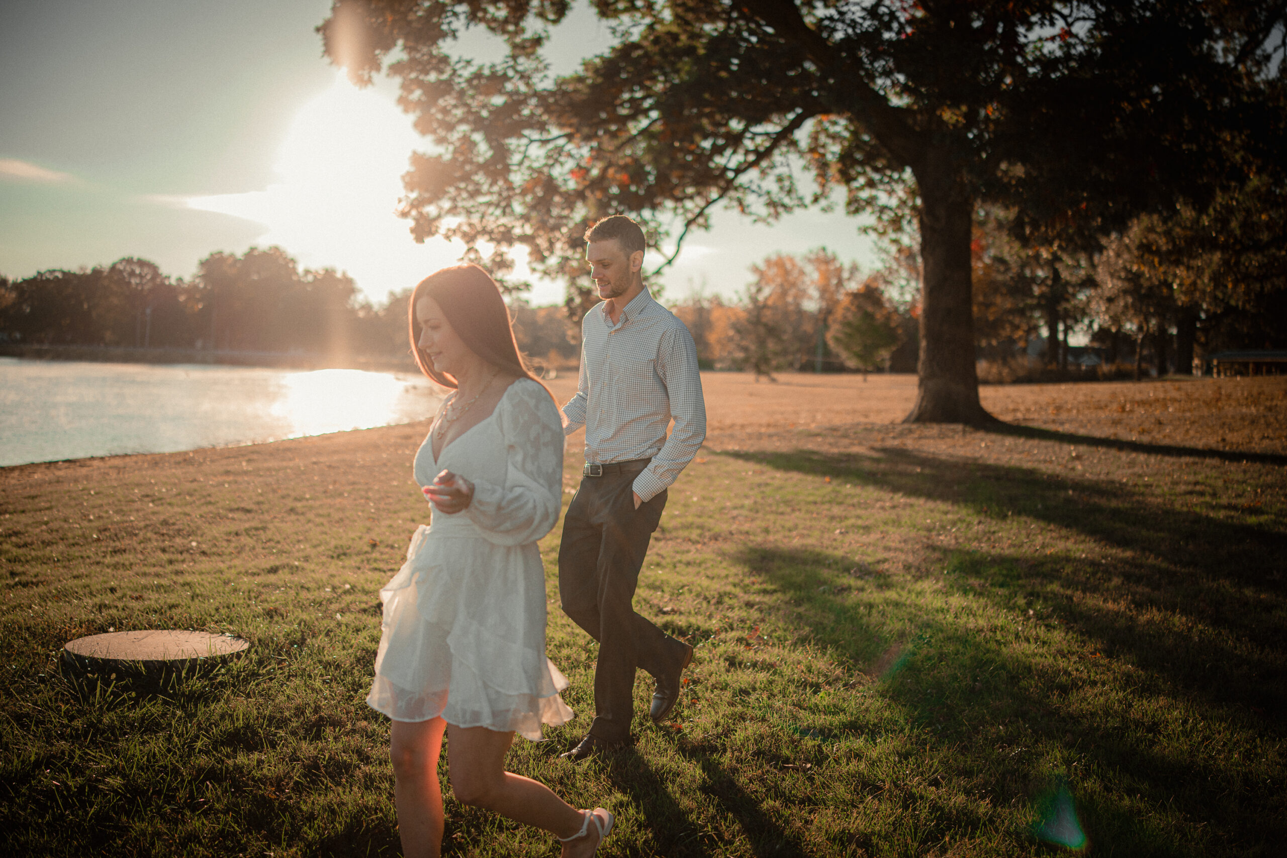 Golden hour couple's photoshoot by the lake in Champaign, IL, captured by Light By Zoey Photography, showcasing warm, natural lighting and candid moments.