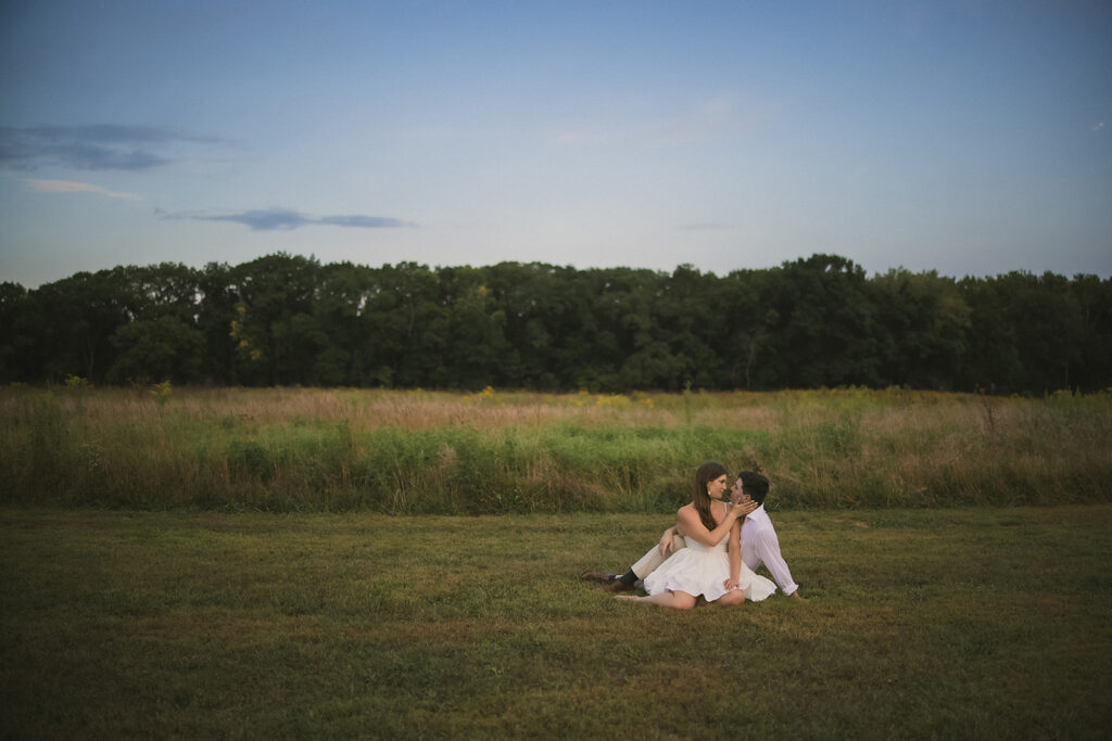 Couple sitting together in an open field during an engagement session at Allerton Park in Monticello Illinois