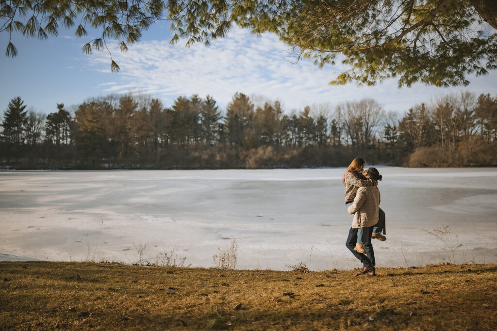 Couple embracing beside the frozen lake during a winter engagement session at Homer Lake, Illinois.