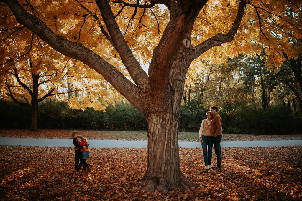 Family portrait beneath colorful fall foliage at Lake of the Woods Forest Preserve in Mahomet, Illinois.