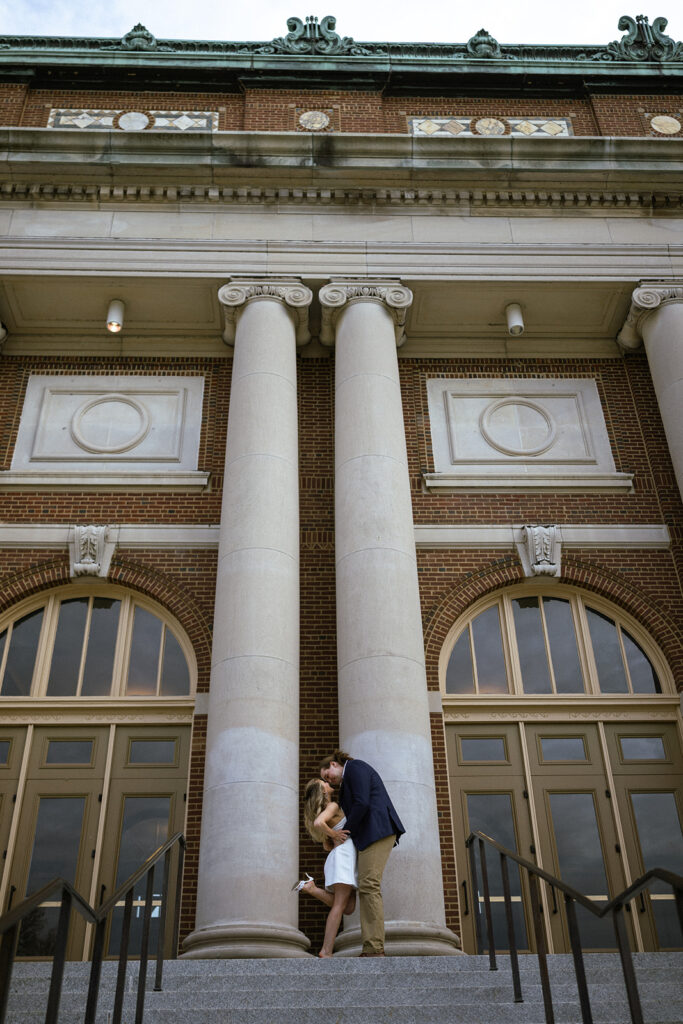 Couple sharing a kiss in front of the grand columns at Memorial Stadium on the University of Illinois campus.