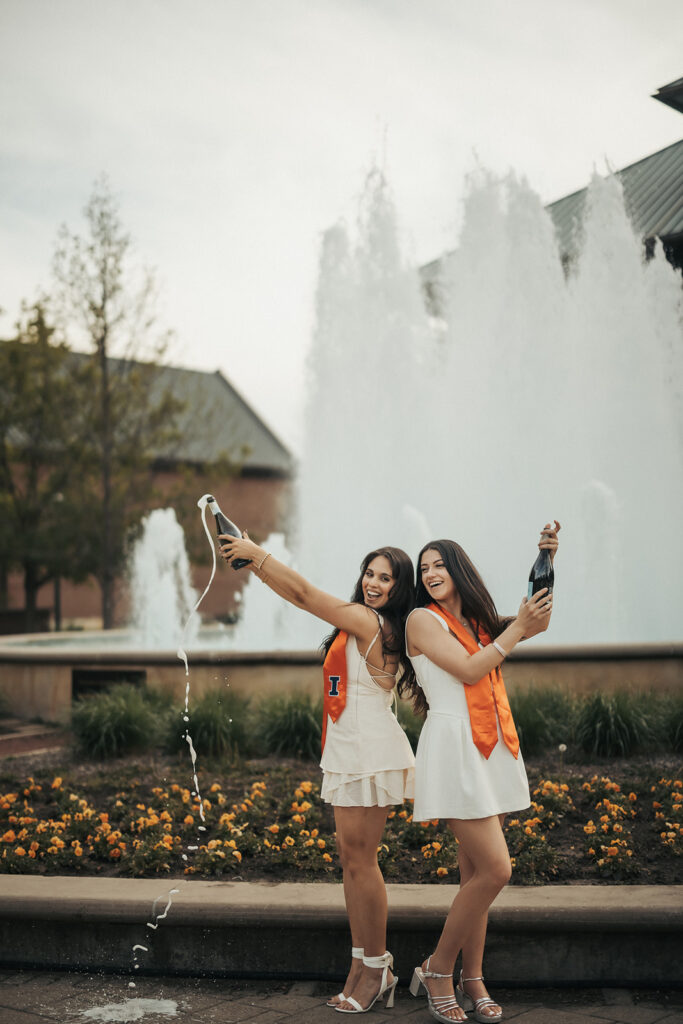University of Illinois graduates celebrating graduation near a campus fountain