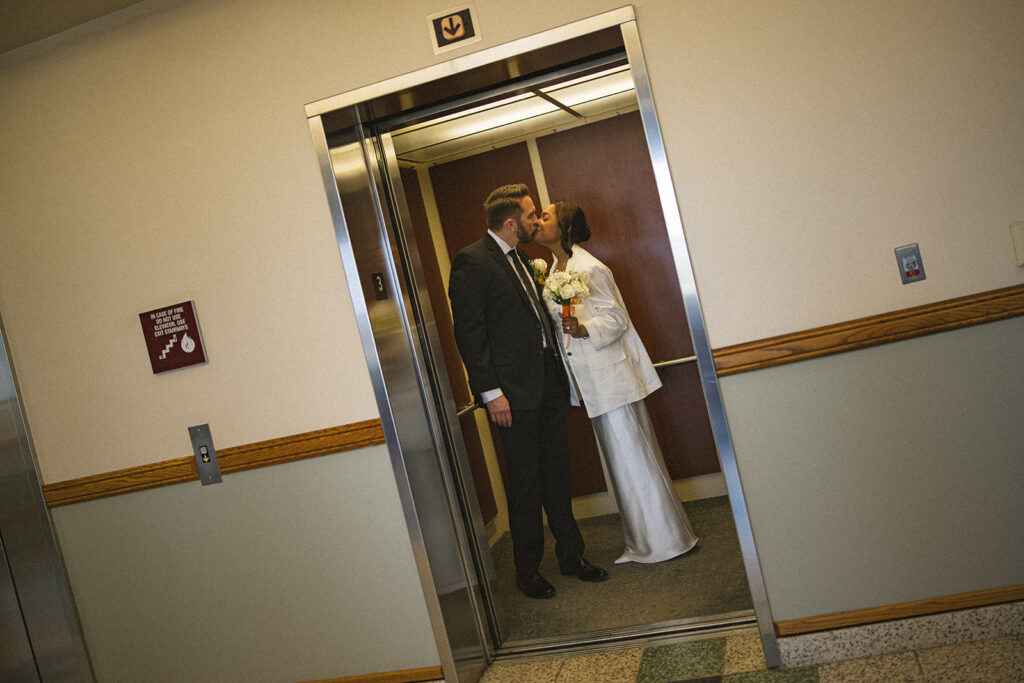 Bride and groom sharing a kiss in an elevator after their Champaign County courthouse wedding in Urbana, Illinois.