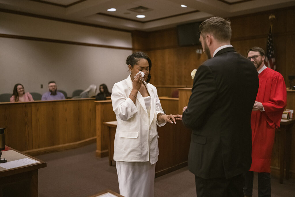 Bride wiping away tears during the ring exchange at a courthouse wedding ceremony in Urbana, Illinois.