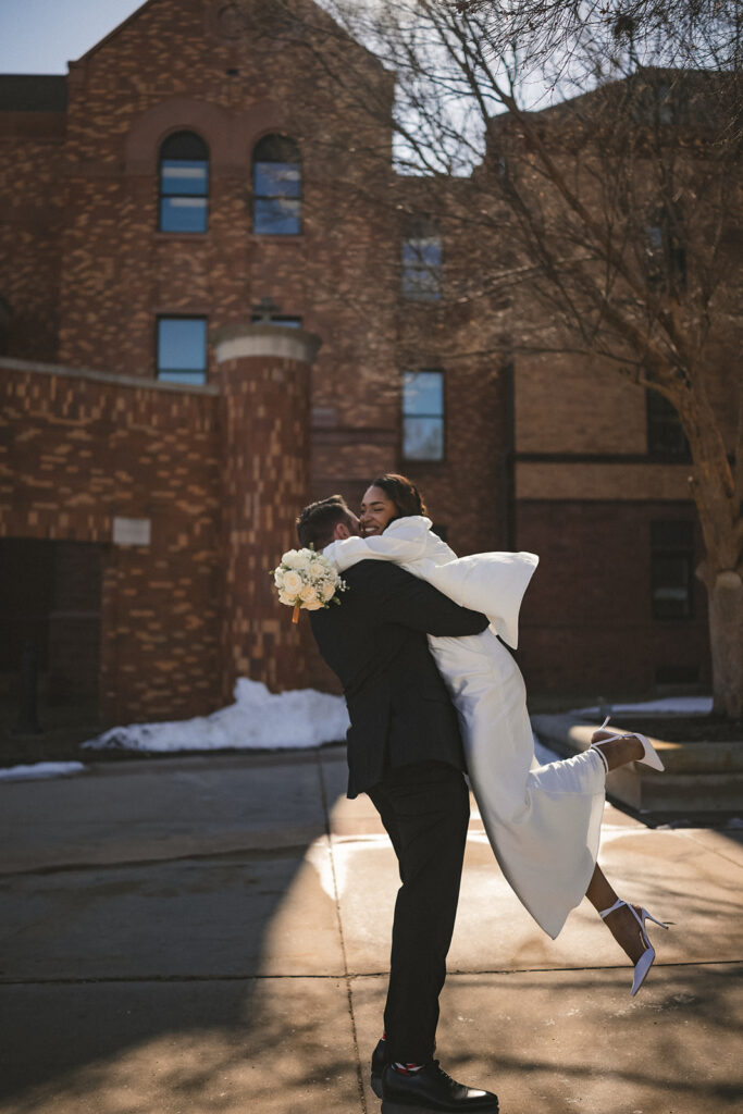 Groom lifting bride outside the Champaign County Courthouse after their intimate courthouse wedding.