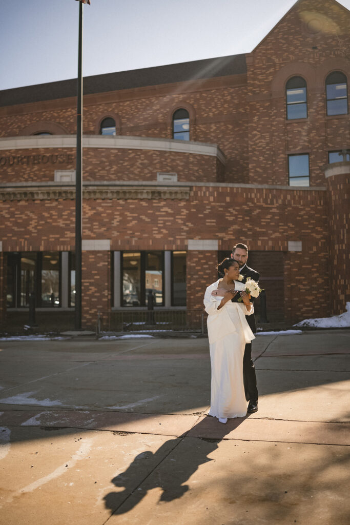 Bride and groom embracing outside the Champaign County Courthouse after their intimate wedding ceremony.