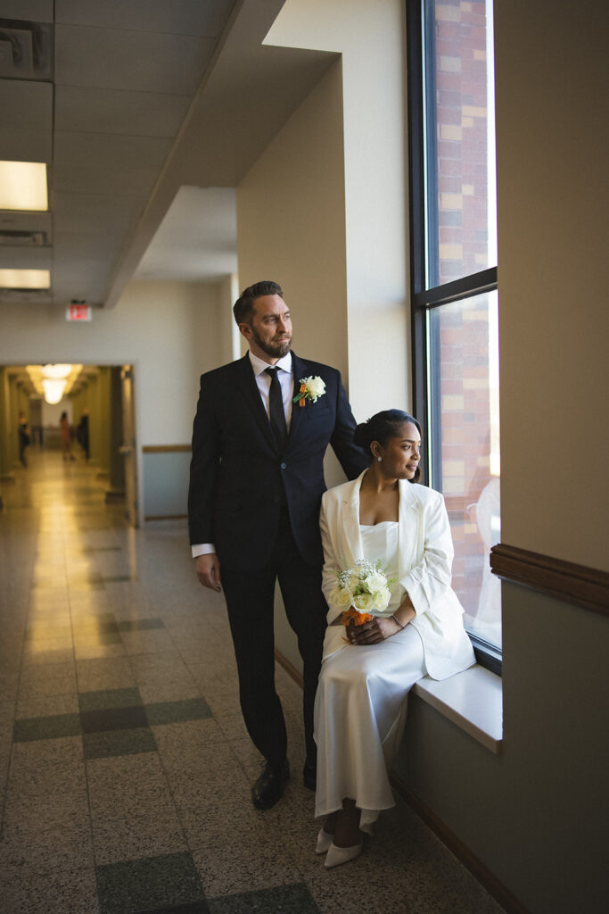 Bride and groom posing by a courthouse window after their wedding ceremony at the Champaign County Courthouse in Urbana, Illinois.