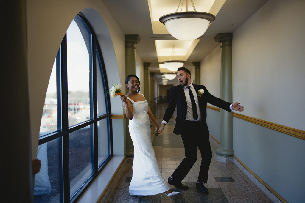 Newlyweds laughing and walking through the courthouse hallway after their wedding ceremony in Urbana, Illinois.