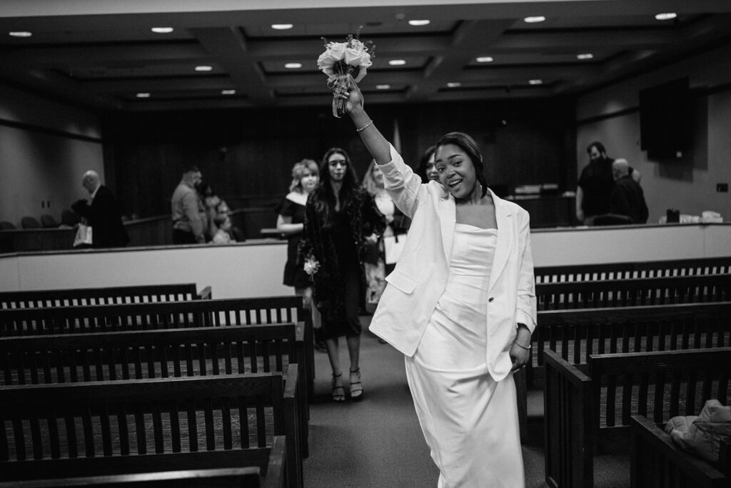 Newly married bride celebrating with her bouquet after a courthouse wedding ceremony in Urbana, Illinois.